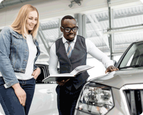 Woman looking at cars with an auto dealership salesperson.
