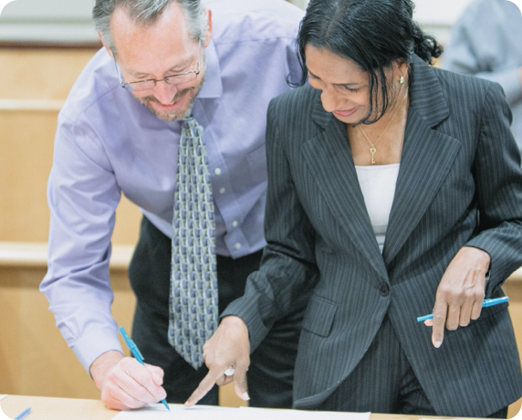 Man and woman in business attire signing papers.