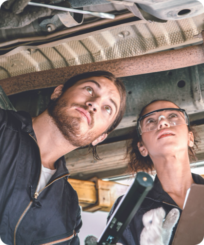 Male and female mechanics working on a car.