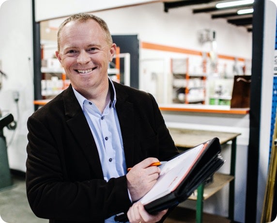 Man smiling while taking notes on a clipboard
